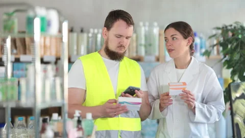 Male builder scans a barcode on a mobile pill box and consults with a female Stock Footage 317528953