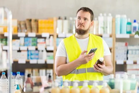Male builder scans code on cough syrup to check expiration date Foto stock