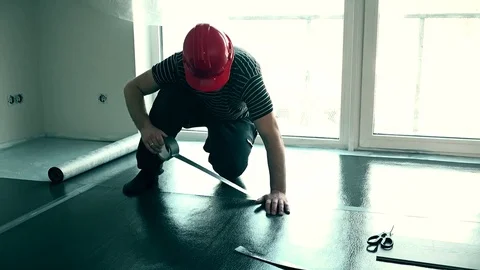 Male builder taping down flooring underlay with tape. Stock Footage 78229039