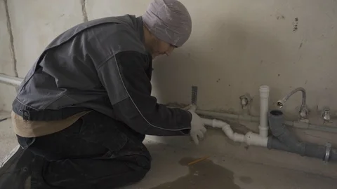 Male builder in work clothes fastens pipes to the wall Stock Footage 101661248