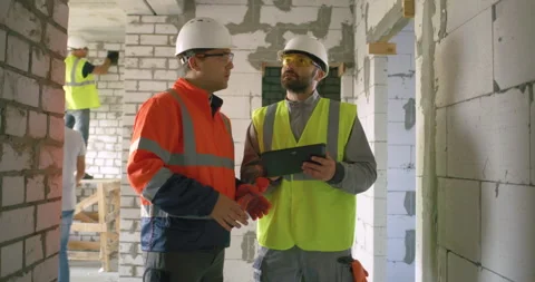 Male builders comparing brick walls with plan Stock Footage 142336775