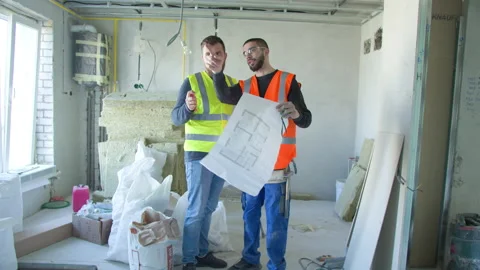 Male builders discussing draft during renovation works Stock Footage 154530570