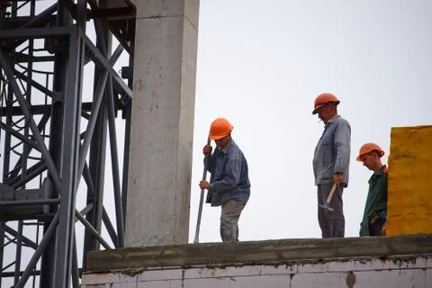 Male builders work on the construction of a multi-story cement building, the  Foto stock