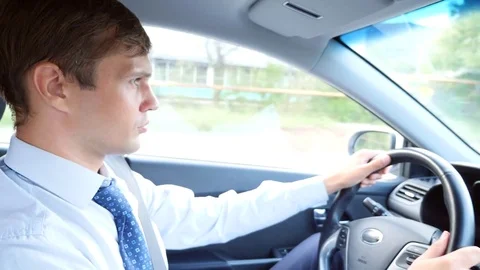 A male businessman in a shirt and tie talks to the passenger, distracted from Stock Footage