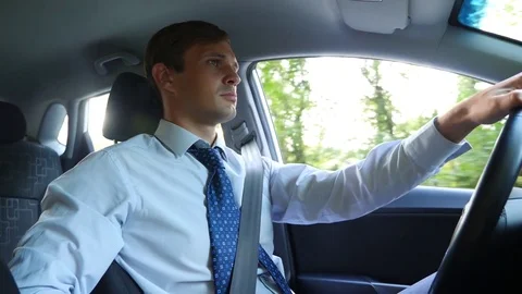 A male businessman in a shirt and tie talks to the passenger, distracted from Stock Footage