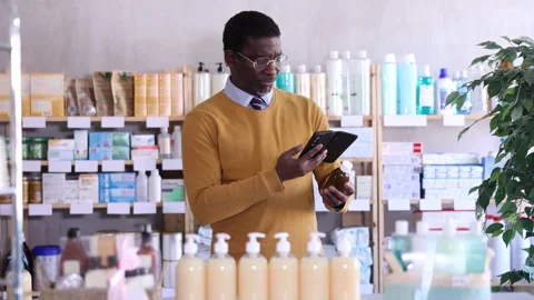 Male buyer in glasses scans code on cough syrup to check the expiration date Stock Footage 318432451