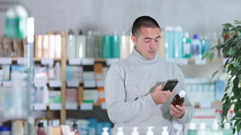 Male buyer scans code on cough syrup to check the expiration date Stock Footage 310320322