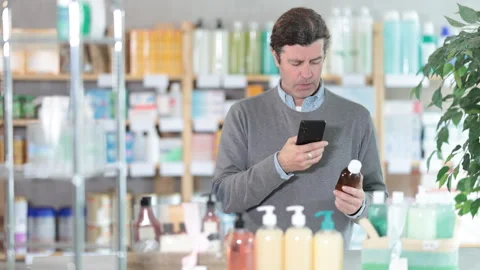 Male buyer scans code on cough syrup to check the expiration date Stock Footage 310964959
