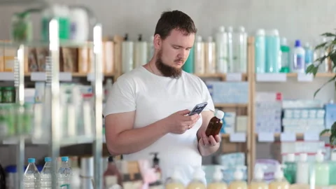 Male buyer scans code on cough syrup to check the expiration date Stock Footage 319492845