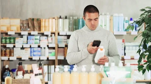 Male buyer scans code on package of skin cream to check the expiration date Stock Footage 313873073