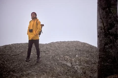 Male with camera walking down the mountain, at foggy weather, alone Stock Photos