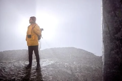 Male with camera walking down the mountain, at foggy weather, alone Stock Photos