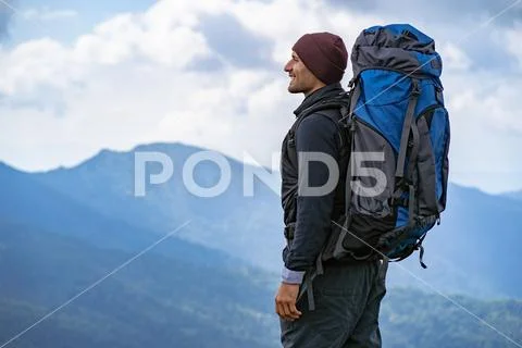 The male with a camping backpack standing on the mountain Stock Photos