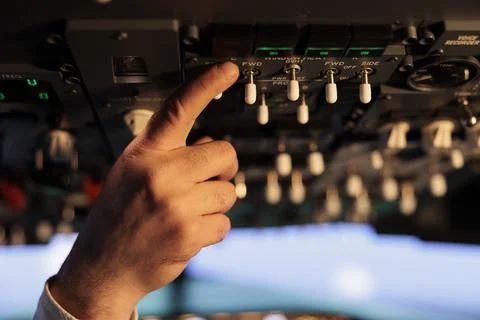 Male captain using control panel in cockpit to fly airborne aircraft Foto stock