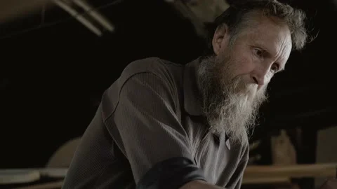Male carpenter with a gray beard, processes a wood product with a planer. An Stock Footage 133064623