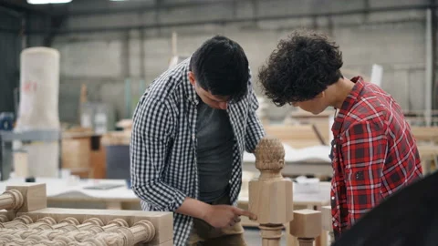 Male carpenter talking to female apprentice in workshop discussing woodware Video stock 113744767