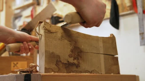 Male carpenter using drawshave to shape new wooden art piece, making wooden Stock Footage 240959466