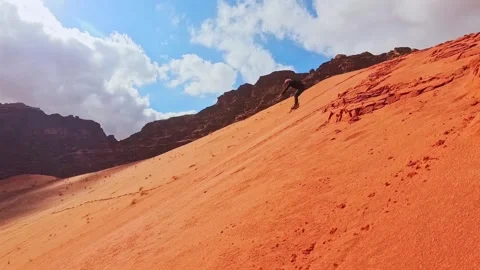 Male caucasian beginner learning solo sandboarding sports on steep red dune.. Stock Footage 330277296