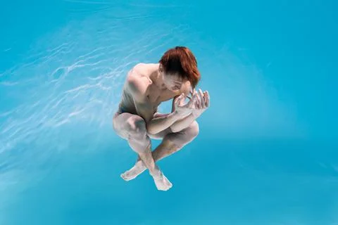 Male Caucasian man swimmer diver dancer swims under water in the sea. Summer  Stock Photos