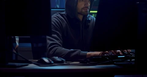 Male Caucasian software developer in a hood working over the hacking programs at Stock Footage 124338525