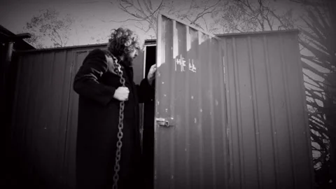 Male with chains on back walking to shed. Stock Footage 196272111