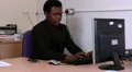 Male chats on his mobile whilst sitting at his desk HD Footage