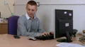 Male chats on his mobile whilst sitting at his desk HD Footage