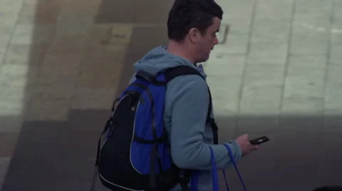 Male checking his iPhone walking down the street Stock Footage 65298863