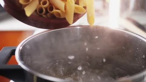 Male chef adding penne pasta into boiling water in pot. Stock Footage 236479692