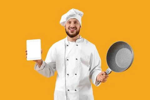 Male chef with blank tablet computer and frying pan on yellow background Stock Photos