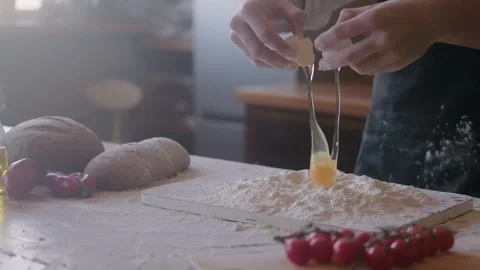 Male chef cracking egg in pile of flour. Slow motion of falling eggs into flour Stock Footage 263884763