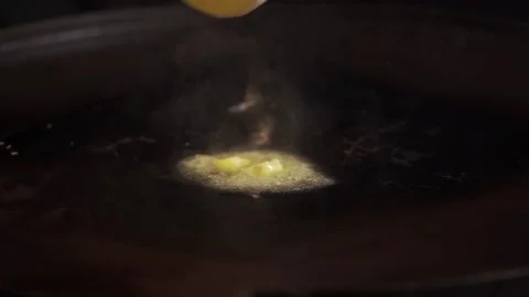 A male chef, fried egg on a black hot pan. Black background Stock Footage 141637115