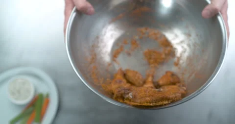 Male chef hands coating uncooked buffalo chicken wings in spice and sauce closeu Stock Footage 199459642