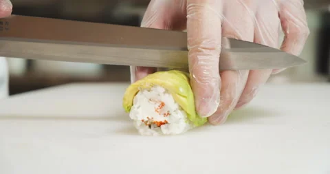 Male chef hands in gloves preparing sushi rolls with avocado in the kitchen Stock Footage 135509750