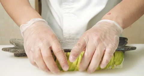 Male chef hands in gloves serving delicious sushi rolls with avocado on a plate. Stock Footage 135510007
