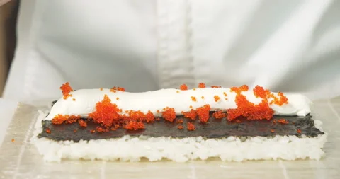 Male chef hands preparing delicious sushi rolls with soft cheese and tobiko Stock Footage 135595152
