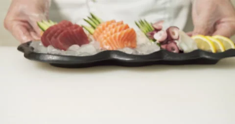Male chef hands serving a dish of fresh fish and octopus slices with vegetables Stock Footage 135597459