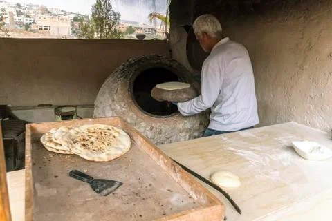 A male chef makes bread in the shape of a heart. Traditional Arabic bread bak Stock Photos
