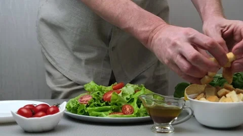 Male chef prepares Caesar salad.Puts croutons in plate with salad.Recipe. Step 3 Stock Footage 170412065