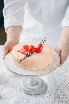 Male chef puts Easter cake kulich with chocolate eggs and willow on table Stock Photos
