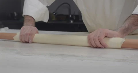 Male chef roll out phyllo dough with a rolling pin. Middle eastern food sweets Stock Footage 285783578