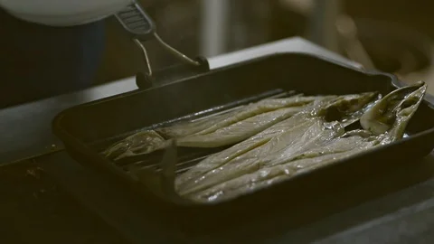 Male chef is smearing fish while frying in pan in restaurant kitchen irrl. Stock Footage 128283554