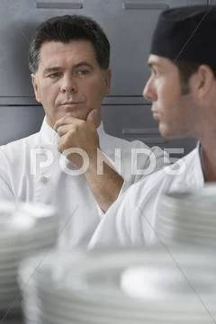 Male Chef Supervising Trainee In Kitchen Stock Photos