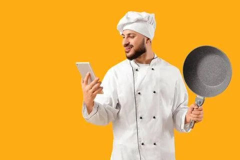 Male chef with tablet computer and frying pan on yellow background Stock Photos