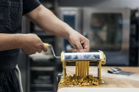 Male chef using machine chop fresh pasta dough Stock Photos