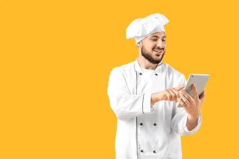 Male chef using tablet computer on yellow background Stock Photos