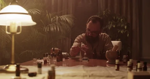 Male chemist mixing oils while creating perfume at table Stock Footage 260986720