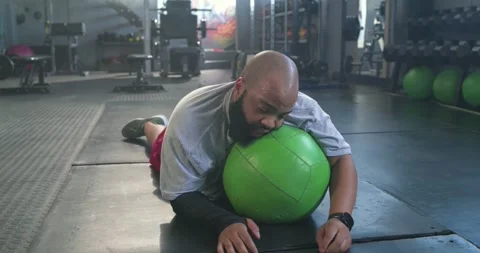 Male client doing pushups on green med ball at gym tiring, collapsing, trainer Stock Footage 335131622