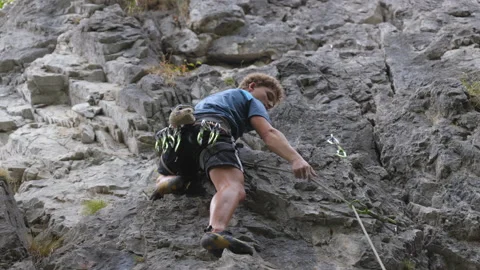 Male climber looking down while in the rocky wall Stock Footage 208940073