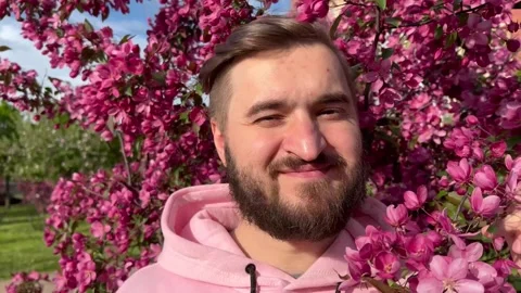 Male closeup portrait. Bearded man in pink hoodie in city park Stock Footage 274242853